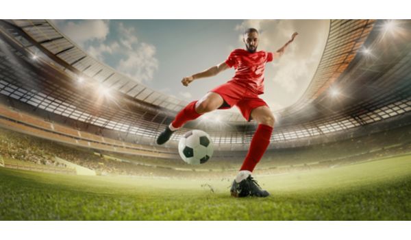 Soccer player kicking ball in red uniform